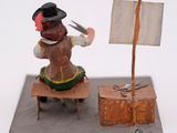 a figurine of a man sitting on a bench with a knife and a flag
