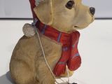 statue of a dog wearing a santa hat and scarf with a tag