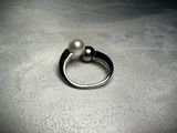 a ring with a pearl on top of it on a table