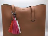 a tan purse with a pink tassel hanging from the handle