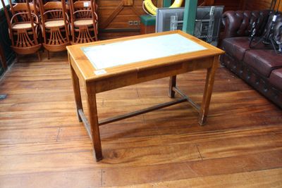 une table en bois avec un plateau en verre, posée sur un parquet