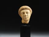 une tête de femme sculptée en ivoire, posée sur un socle noir