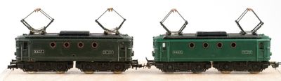 two green trains sitting side by side on a wooden table