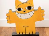 a yellow cat that is standing on a wooden stand