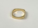 gros plan d'une bague en or sur une surface blanche