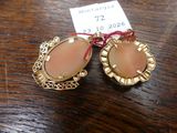 pair of gold tone earrings with pink stones on a wooden table