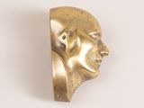 brass sculpture of a man ' s head on a white surface