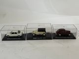 three different model cars are in a display case on a white surface