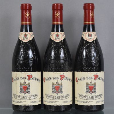 trois bouteilles de vin rouge posées sur une table en verre