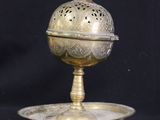 an antique brass plate with a lid and stand on a black background