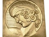une image représentant une plaque en or sur laquelle figure la tête d'une femme
