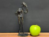 a statue of a man holding a hat next to an apple on a table