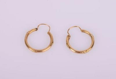 une paire de boucles d'oreilles en or sur fond blanc