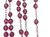 rosary with a cross on a chain and a purple beaded necklace