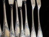 cinq cuillères en argent et six fourchettes en argent posées sur un fond noir