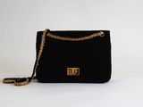 un sac à main noir muni d'une chaîne dorée sur fond blanc