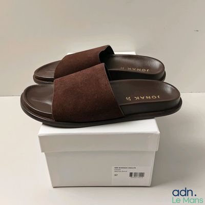 une paire de pantoufles marron posée sur une boîte blanche