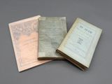 trois vieux livres posés l'un sur l'autre sur une table