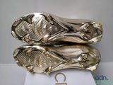 a close up of a pair of gold soccer cleats on a white surface
