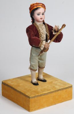 une figurine représentant un garçon tenant un bâton, posée sur une boîte