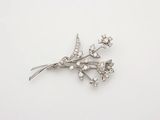 une photo d'une broche en forme de fleur de diamant posée sur une surface blanche