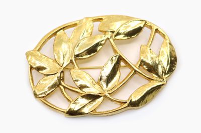 un gros plan d'une broche en or ornée de feuilles
