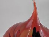 a red vase that has a black hole in it