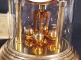 a gold clock inside of a glass dome on a table