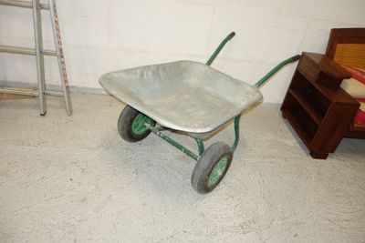 a wheelbarrow in the corner of a room with a ladder