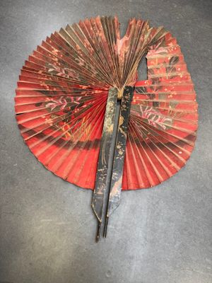 un éventail rouge surmonté d'une paire de ciseaux