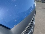 the front of a blue car with a dent in it ' s bumper