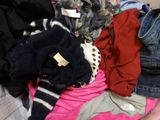 un tas de vêtements sur un lit sur lequel sont posés d'autres vêtements
