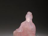 a pink jade figurine of a woman sitting on a rock