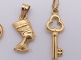 three gold charms with a heart and a key on a white surface