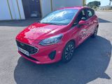 une Ford Fiesta rouge garée devant un immeuble