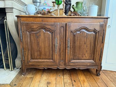 une armoire en bois à deux portes, surmontée d'un vase en verre