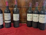 six bottles of wine are lined up on a red table cloth