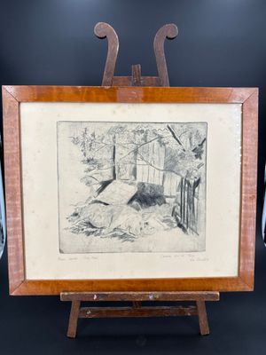 une vieille photo représentant un chien allongé par terre devant un chevalet en bois