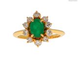 gros plan d'une bague avec une pierre verte entourée de diamants