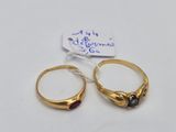 pair of gold rings with garnetts on them sitting on a white surface