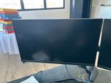 two computer monitors sitting on a desk with wires
