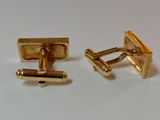 pair of gold plated cufflinks on a white surface