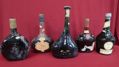 several bottles of wine are lined up on a red surface