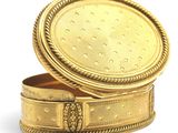 a gold box with a lid on a white surface