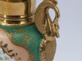 a green vase with a gold handle on a white background