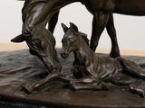 a bronze statue of a horse and a foal on a table