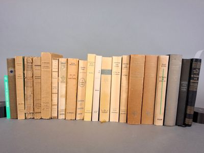 plusieurs vieux livres sont alignés sur une étagère, les uns à côté des autres