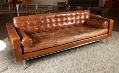 un canapé en cuir marron posé sur un tapis dans un salon