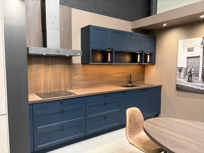 une cuisine avec une table et des chaises, et un tableau accroché au mur