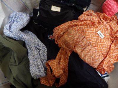 a pile of clothes sitting on the floor next to a suitcase